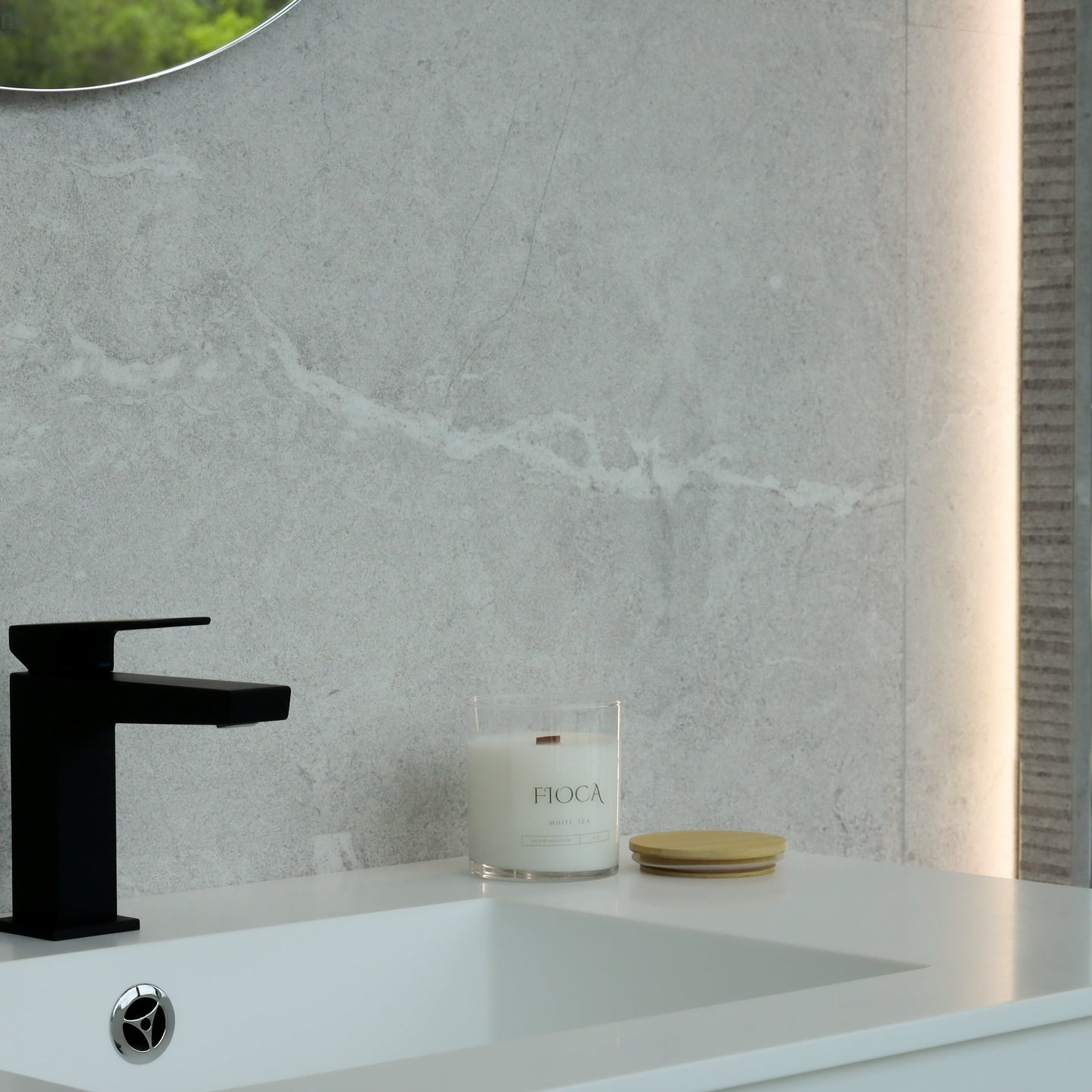Fioca candle set on a minimalist white sink counter, complementing luxury bath products in a modern bathroom setting