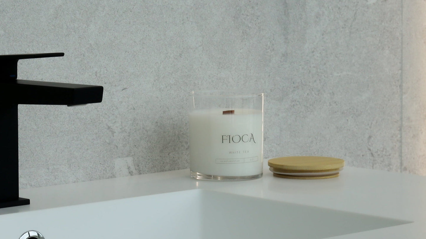 Fioca candle set on a minimalist white sink counter, complementing luxury bath products in a modern bathroom setting